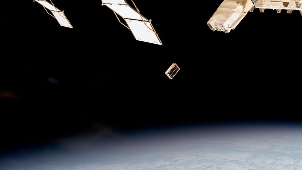 Um CubeSat acabado de libertar da Estação Espacial Internacional, a afastar-se em órbita com a Terra por baixo