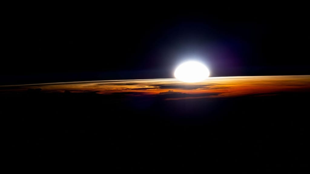 Nascer do Sol visto em órbita a partir da Estação Espacial Internacional, com a luz a rasgar o limbo curvo da Terra e as camadas coloridas da atmosfera