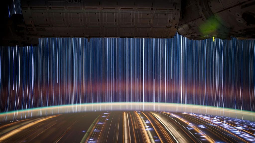 Rastos de estrelas e luzes de cidades numa exposição longa feita da Estação Espacial Internacional